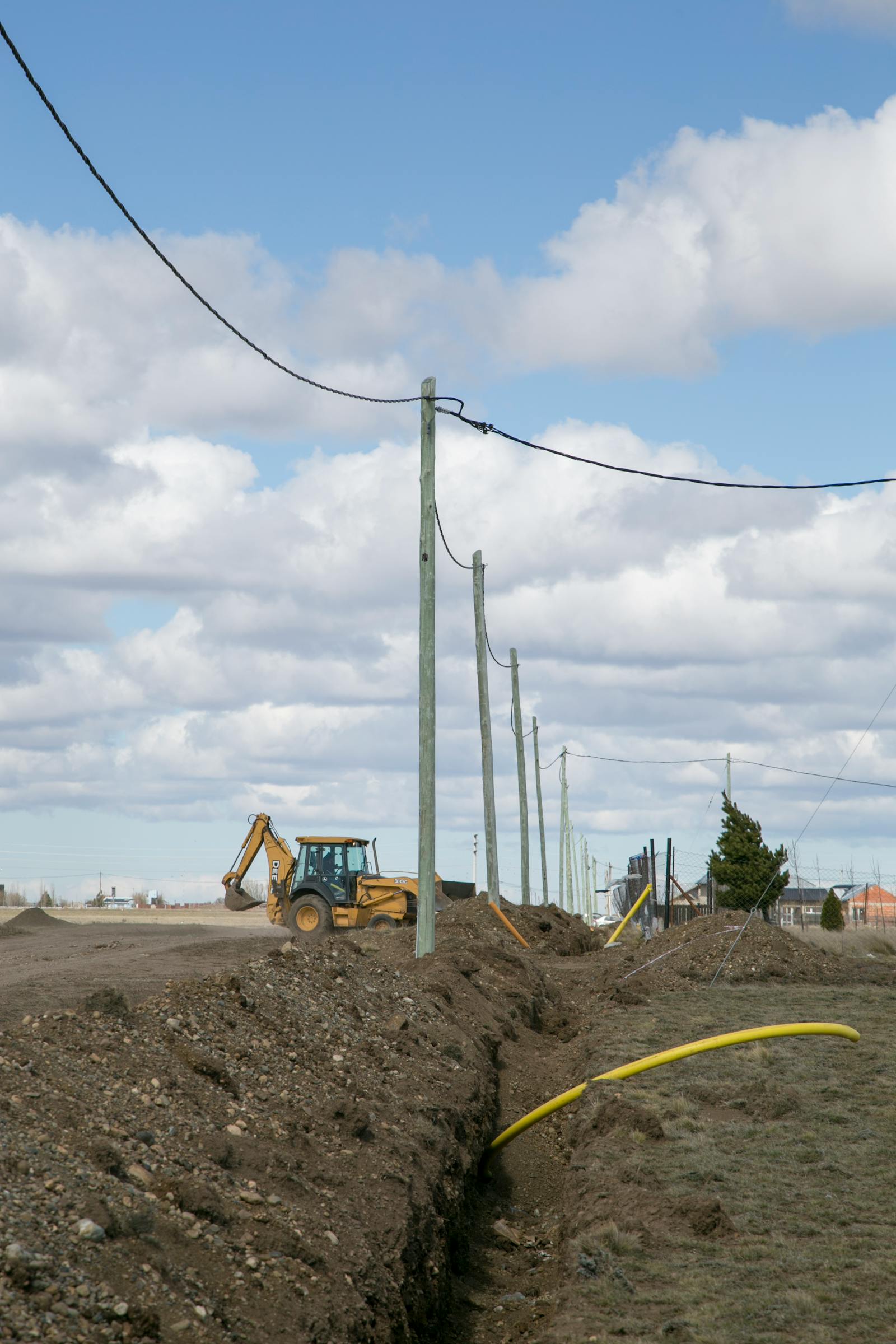 Backhoe excavating a utility trench under overhead power lines
