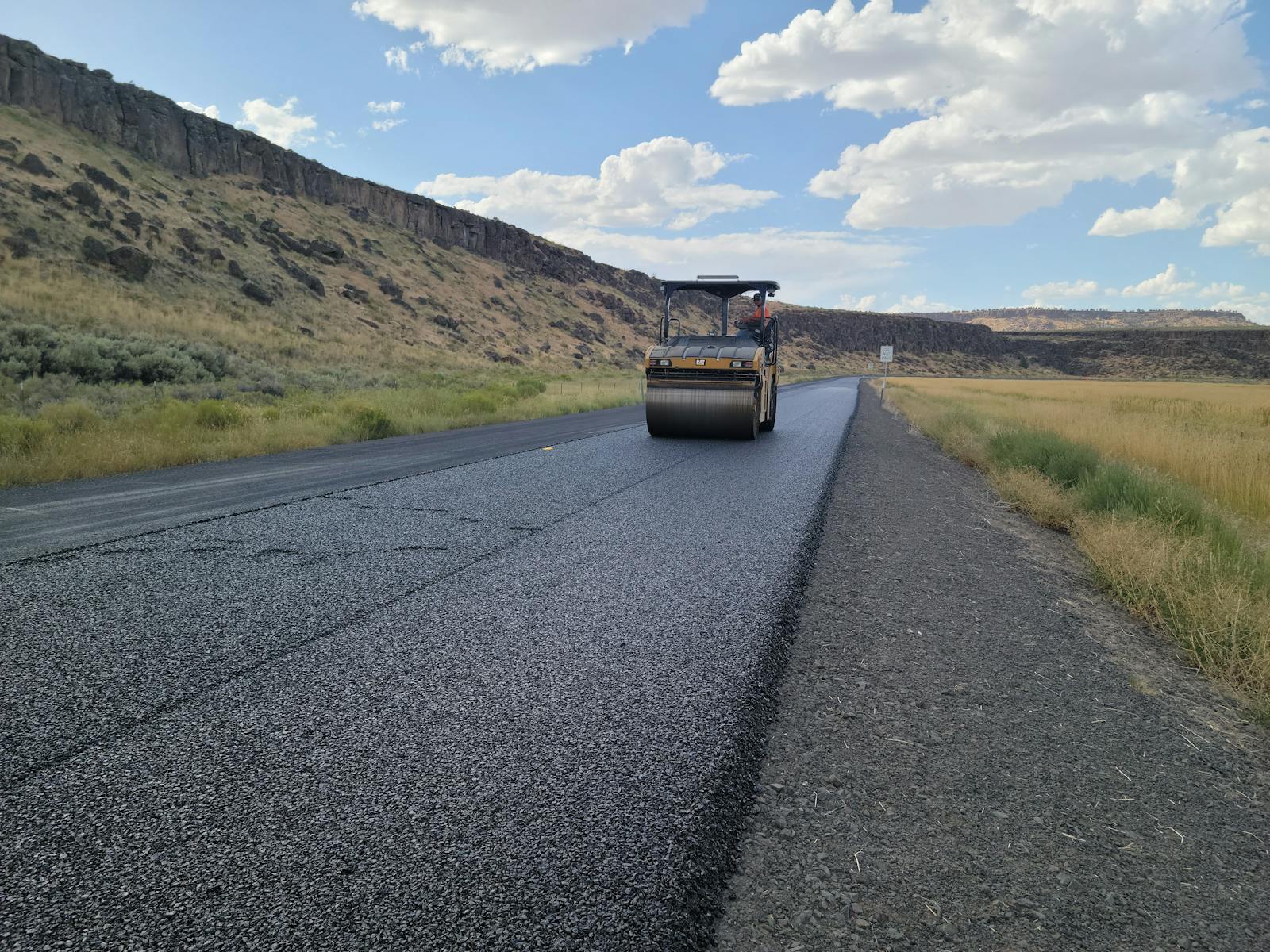 Asphalt road resurfacing crew with roller compactor